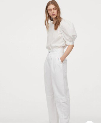 A woman wearing white pants and white top