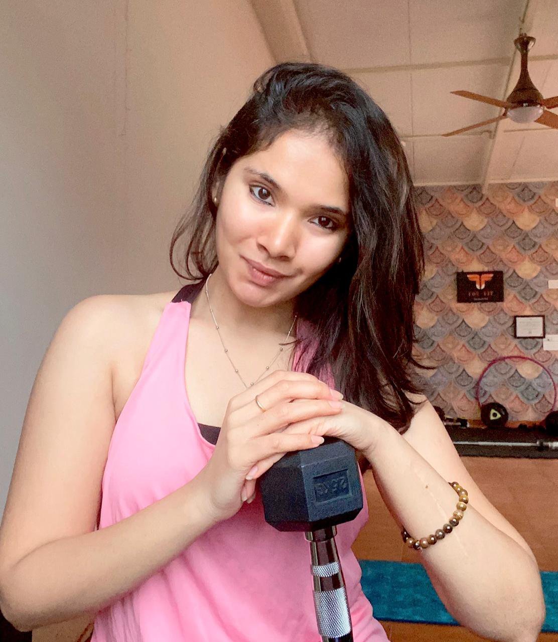 A woman smiling with a dumbbell in her hands