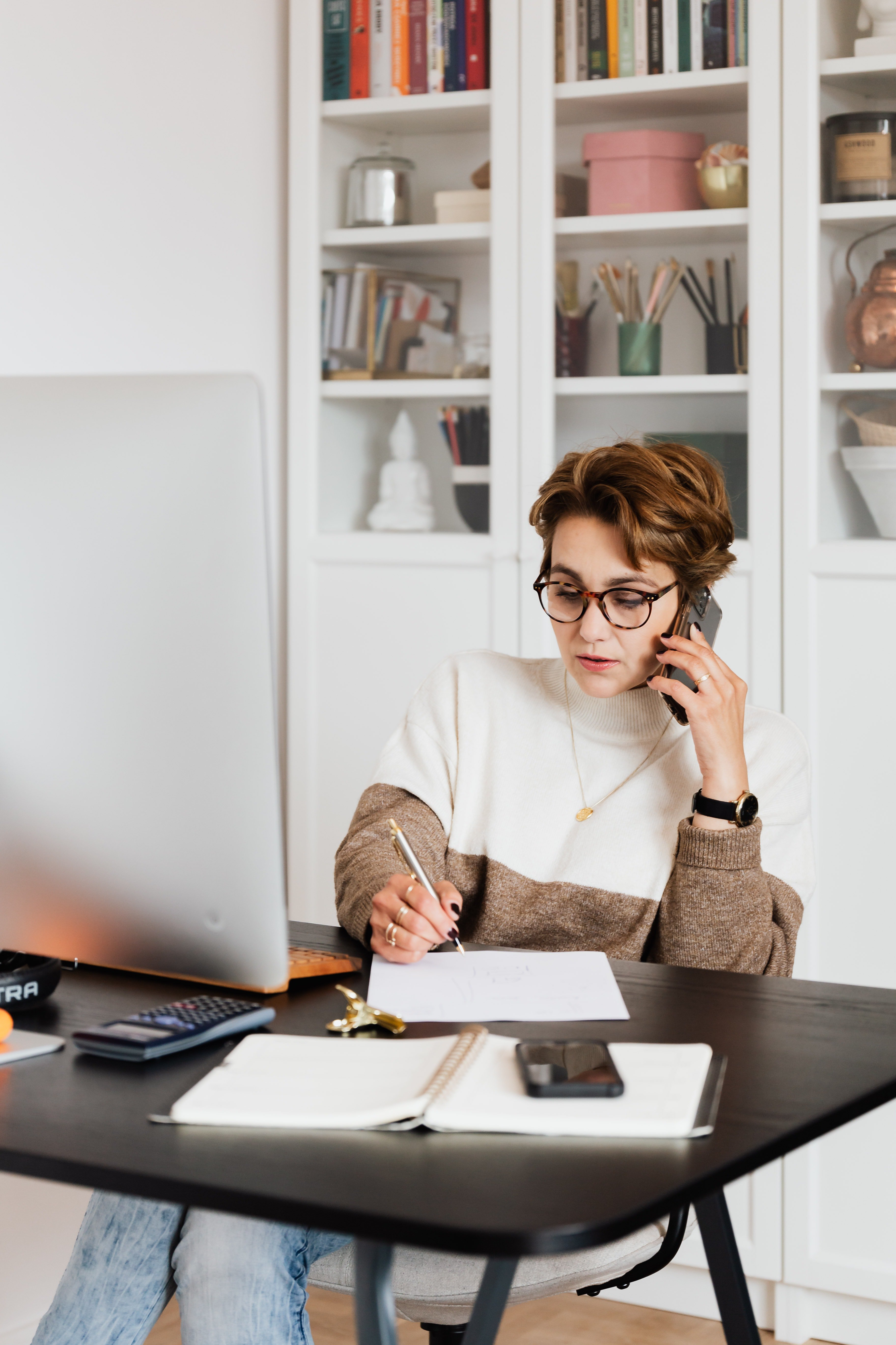 a woman talking on phone while writing something