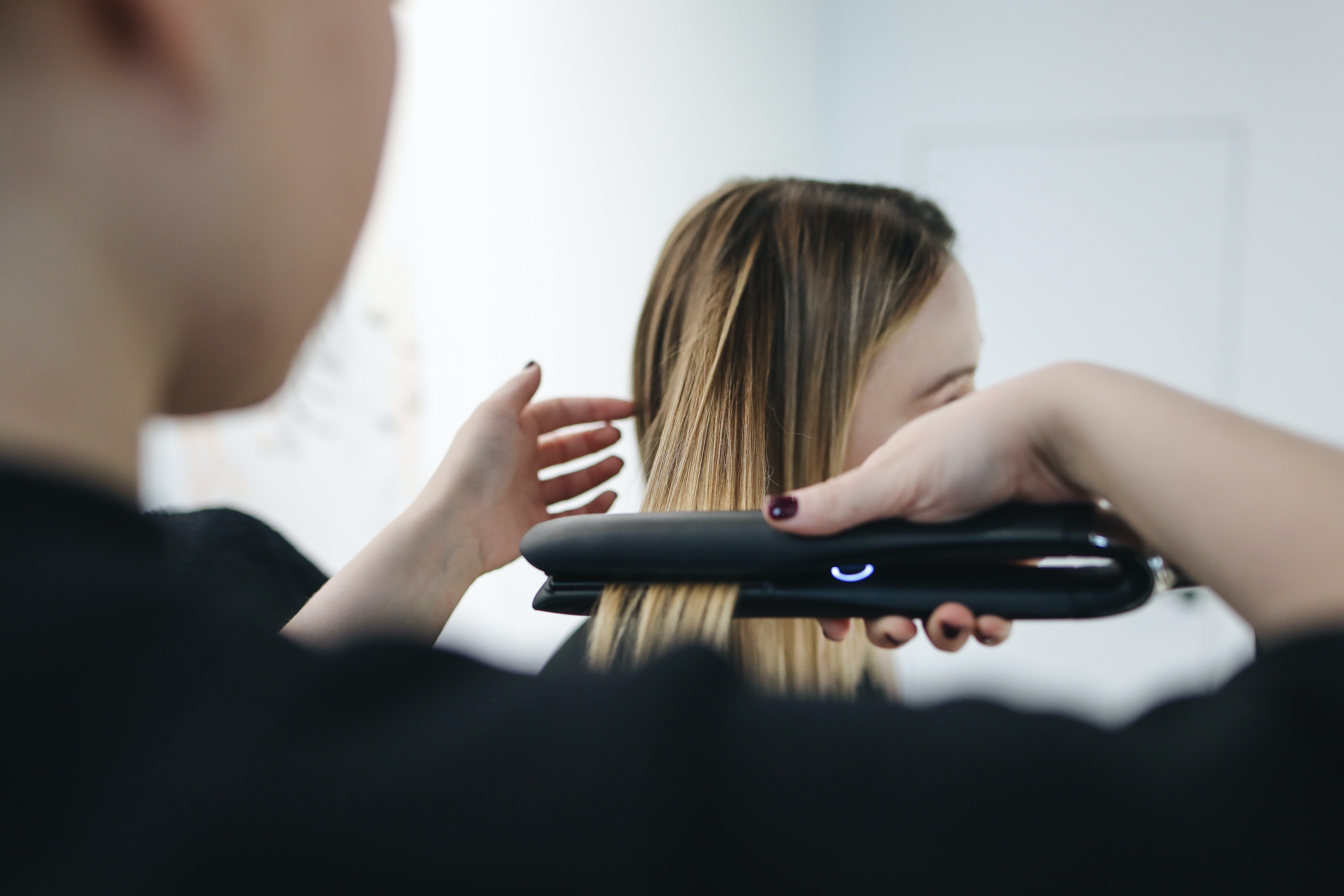 a person straightening woman's hair with a hair straightener